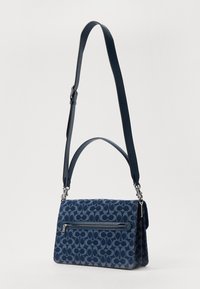 Navy blue fabric handbag with a textured pattern, top handle, and adjustable shoulder strap. Features a front zipper pocket.
