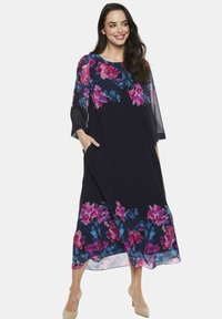 Granatowa sukienka maxi w kwiaty z przejrzystymi rękawami, z żywymi różowo-niebieskimi wzorami u dołu, posiada kieszenie, jest wykonana z miękkiego materiału i ma luźny krój.