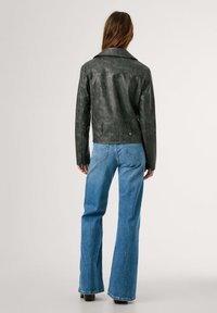 Must kasukatega nahkjope, millel on krae, selja õmblused ja küljetaskud. Kombineeritud siniste kõrge vöökohaga laienevate teksadega, mis näitavad lõdvestunud istuvust.