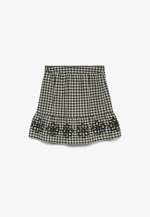 Jupe à carreaux noir et blanc avec taille élastique et broderie florale noire le long de l'ourlet volanté inférieur.