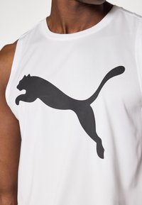 Fehér ujjatlan sportpóló, légáteresztő anyagból készült, elöl egy nagy, fekete Puma-logóval, amely ugró formában van elhelyezve.