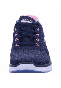 Zapatillas Skechers con parte superior texturizada en azul marino, detalles en rosa en los cordones y suela blanca. Presenta un collar suave y detalle del logo en el costado.