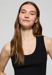 Top a maniche corte nero con costine, caratterizzato da un scollo a barco e spalline lunghe, che mette in risalto una texture liscia e una silhouette aderente.