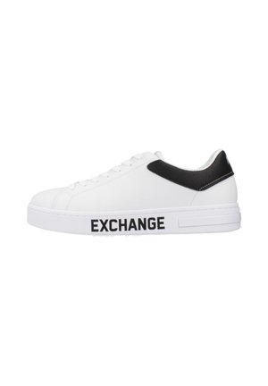 Zapatilla blanca con parte superior de cuero texturizado, acento negro en el talón y logo "EXCHANGE" impreso en negrita negra en el costado.