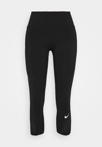 Czarne legginsy 3/4 wykonane z elastycznego materiału, z wysokim stanem i białym logo Nike na lewym nogawce, z dziurkowanym detalem w pobliżu dołu.