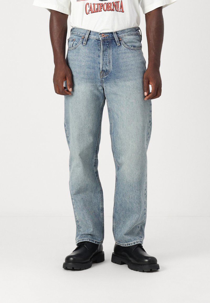 Light wash denim jeans with a straight leg design, featuring a five-pocket style and slight fading. Paired with black ankle boots.