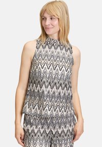 Czarny i biały bezrękawnik z wysokim dekoltem, z wzorem fal oraz teksturowaną powierzchnią. Lekka i luźna konstrukcja.