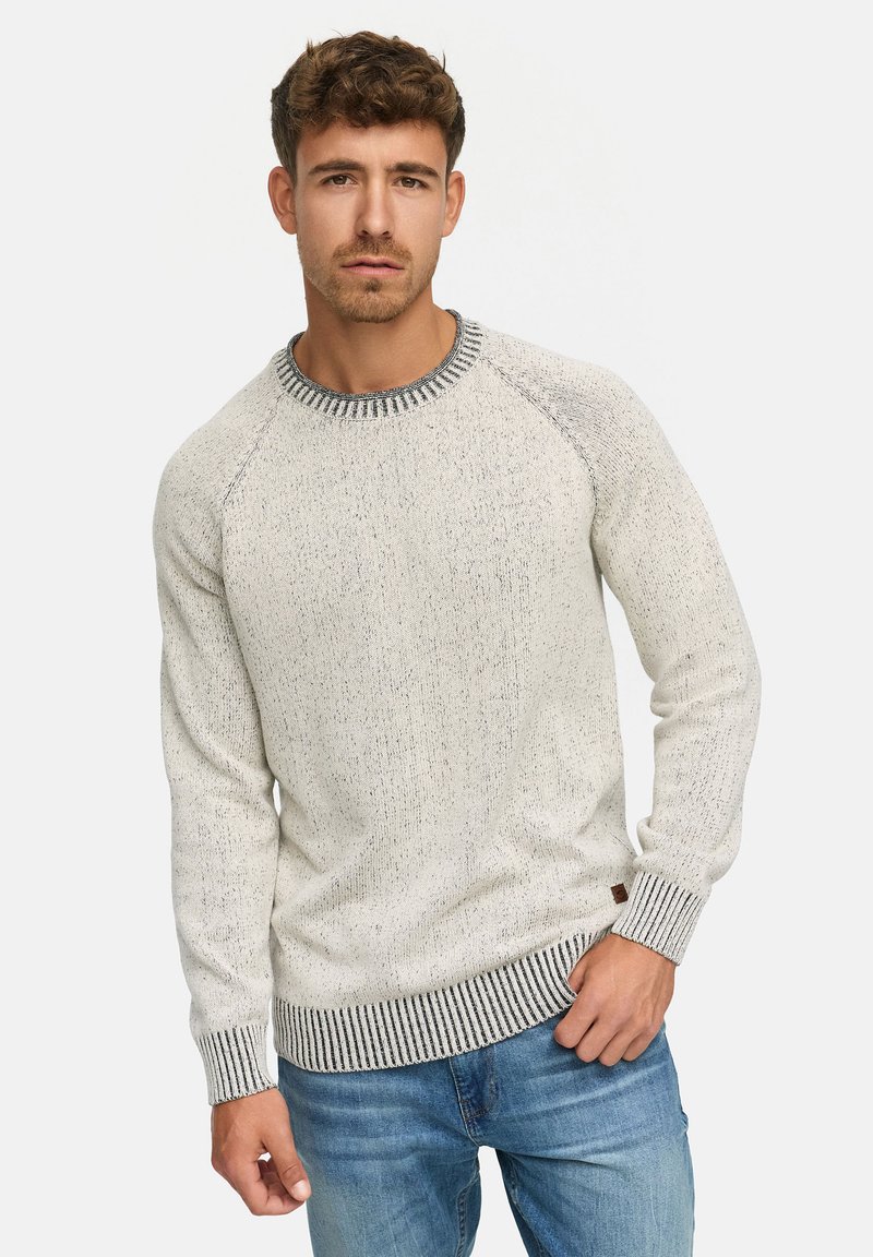 Lichtgrijze gebreide trui met een textuurafwerking. Heeft een gemusterd ronde halslijn en contrasterende gestreepte manchetten en zoom. Gecombineerd met blauwe jeans.
