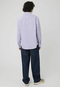 Chemise à rayures lavande à manches longues avec un col pointu, des poignets boutonnés et un ourlet arrondi, associée à un jean en denim foncé à coupe ample.