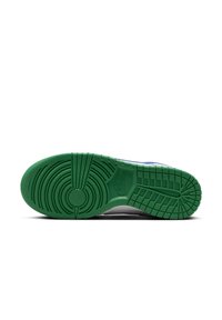Semelle en caoutchouc verte d'une basket avec des motifs de bande de roulement circulaires et en grille, et logo Nike embossé près du médio-pied.