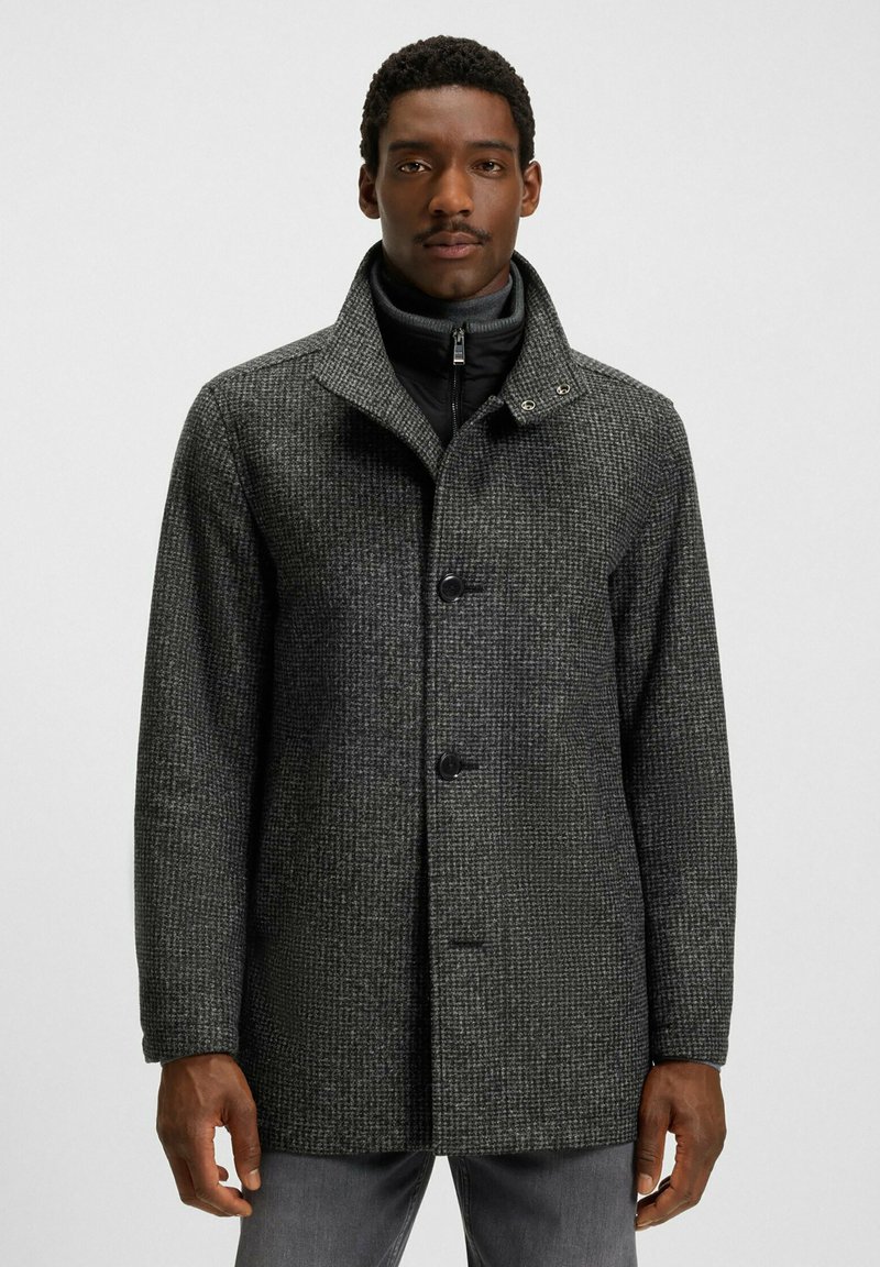 Cappotto grigio a fantasia con colletto, dotato di chiusura a bottoni e strato interno con cerniera. Realizzato in tessuto testurizzato, con maniche lunghe.
