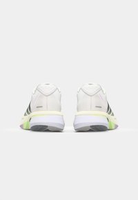 White athletic shoes with a textured mesh upper, contrasting black stripes, and a multi-colored sole featuring green and purple accents.