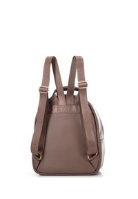 Zaino in pelle marrone con finitura testurizzata, spallacci in tessuto regolabili con logo impresso, e forma arrotondata. Accessori in metallo dorato visibili.