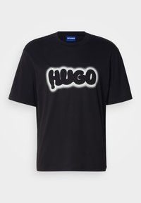 Juoda medvilninė marškinėlė su trumpomis rankovėmis. Priekyje yra didelis „HUGO“ logotipas baltos spalvos su suliejimo efektu.