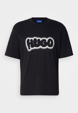 Black T-shirt made of cotton with short sleeves. Features a large "HUGO" logo in white with a blurred effect on the front.