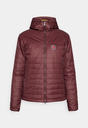 Burgundi színű, kapucnis, szigetelt dzseki, amely elöl cipzárral záródik és vízszintes steppeléssel van ellátva. A bal mellrészen egy logós folt található.