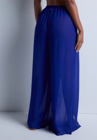 Pantalons palazzo bleu en tissu léger avec une taille élastique confortable, qui tombe et drape de manière élégante.