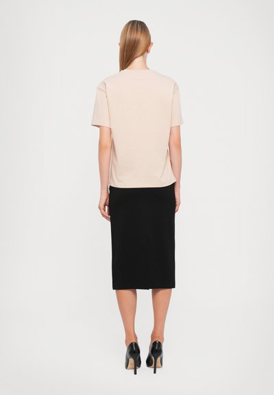 Light pink t-shirt with short sleeves, paired with a fitted black midi skirt and black high-heeled shoes; smooth texture, simple design.