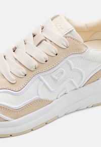 Sneaker in suede beige e tessuto bianco texturizzato con lacci piatti, colletto imbottito e dettaglio del logo impresso sul lato, caratterizzato da una spessa suola bianca.