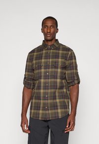 Groene en marineblauwe geruite overhemd met button-down kraag en twee borstzakken, met opgerolde mouwen en bruine accenten.
