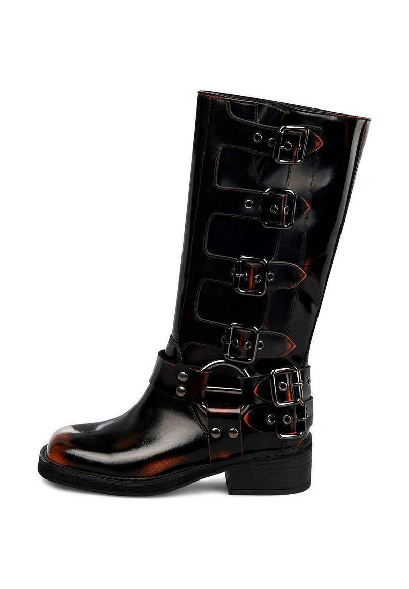 Bota alta de cuero negro brillante con cuatro hebillas laterales y una correa adicional de doble hebilla alrededor del tobillo, sobre un tacón bajo apilado.