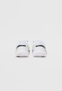Weiße Sportschuhe mit einem atmungsaktiven Mesh-Obermaterial, schwarzen Akzenten und neon-grünen Highlights an der Seite sowie strukturierten Gummisohlen.