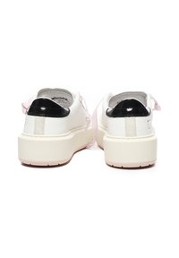 Zapatillas blancas con un acento en el talón de cuero charol negro, cordones rosas y una suela gruesa blanca con un fondo de rosa claro.
