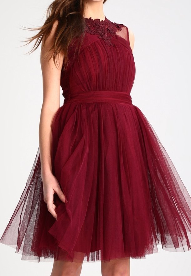 Femme portant une robe sans manches en tulle bordeaux avec un détail en dentelle au niveau de l'encolure et une taille ajustée.