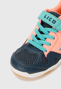 Basket classique avec une partie inférieure bleu marine, un dessus rose et des lacets turquoise. Des panneaux de ventilation en maille et une semelle en caoutchouc améliorent la respirabilité.