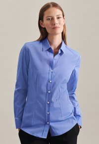Lichtblauw button-up shirt met lange mouwen, een puntige kraag en een subtiel textuurpatroon. Witte knopen en een getailleerde pasvorm met een gebogen zoom.