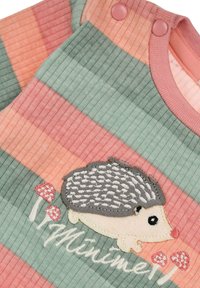 Gestreifter Stoff-Overall in Pastellfarben (rosa, grün, pfirsich), mit einem Igel-Stickdesign und Knopfdetails an der Schulter.