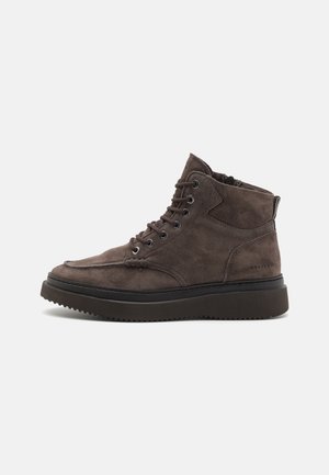 Brown suede ankle boots with a round toe, featuring a lace-up design, padded collar, and black rubber sole with textured tread.