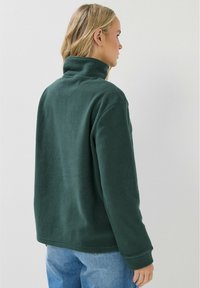 Pullover in fleece verde scuro con colletto alto e maniche lunghe. Texture morbida, vestibilità rilassata. La vista mostra il retro e parte dei lati.