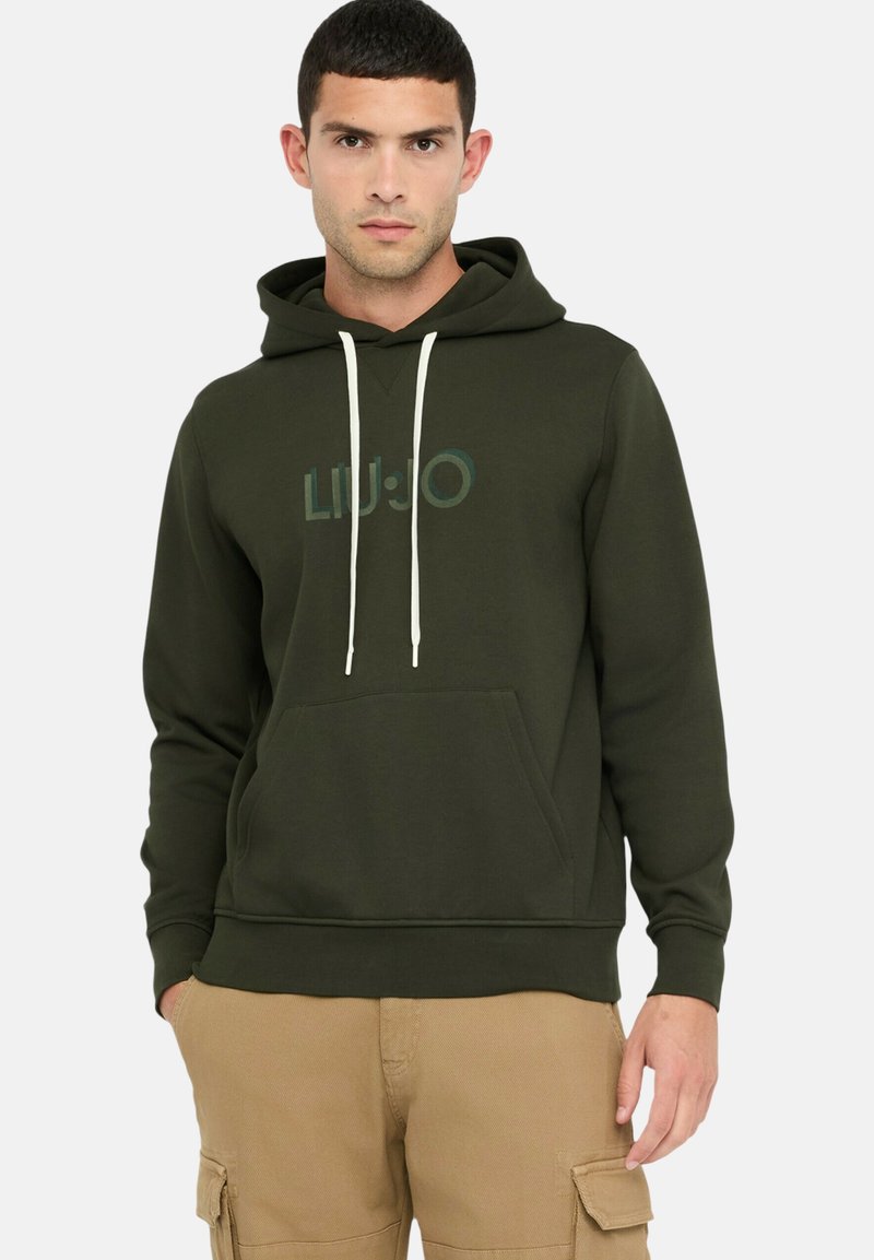 Donkergroene hoodie met een voorzak, verstelbare witte trekkoorden en een licht vervaagde logografiek. Zachte stoftextuur.