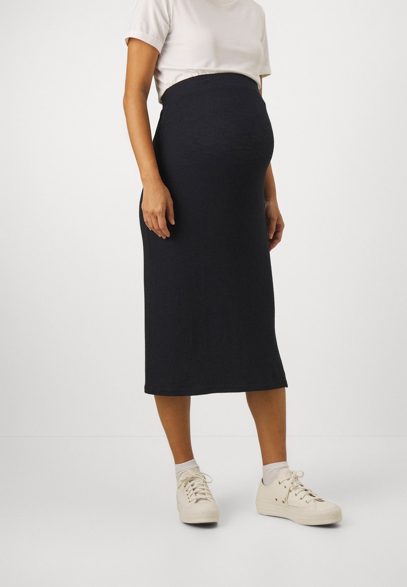 Jupe midi bleu marine foncé avec une taille cintrée, fabriquée en tissu doux. Associée à des baskets blanches et un t-shirt neutre.