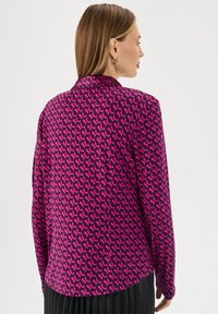 Camicia aderente di un vivace rosa con un motivo geometrico caratterizzato da forme intrecciate; tessuto morbido e design del colletto classico.