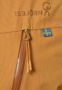 Orange tyg med en slät textur har en brun dragkedja och gula sömmar. Varumärket "ISBJÖRN" är präglat ovanför dragkedjan, tillsammans med en blå och gul flagga.