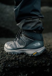Szare buty do wędrówek z teksturowaną syntetyczną cholewką, wodoodporną podszewką Gore-Tex i podeszwą Vibram zapewniającą przyczepność. Posiada logo oraz wzmocniony czubek.