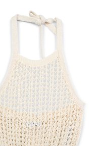 Top halter lavorato a maglia in bianco sporco, caratterizzato da un design in crochet morbido con trama aperta, spalline regolabili e una piccola etichetta vicino all'orlo.