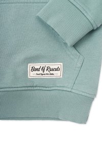 Mintgrön sweatshirt tillverkad av ekologisk bomull. Har ribbade muddar och fåll med en etikett som säger "Band of Rascals" i svart text.