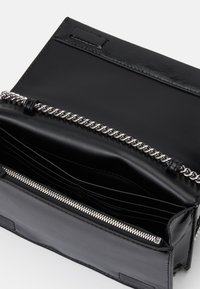 Black leather handbag featuring a silver chain detail and zip closure, with multiple compartments and card slots inside.
