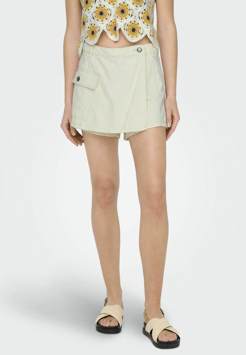 Lichtbeige skort met een zijvak, voorzien van een knoopsluiting en een ontspannen pasvorm. De stof heeft een gladde textuur en een natuurlijke afwerking.