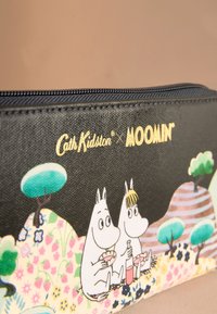 Juoda pieštukų dėklas su užtrauktuku, vaizduojantis Muminų personažus gėlių peizaže, su auksiniu logotipu ir tekstūruota paviršiaus apdaila.