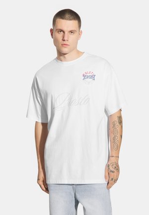 Biała bawełniana koszulka z okrągłym dekoltem, krótkimi rękawami i nadrukiem w kolorach czerwonym i niebieskim, z napisem "ATHLETIC 1999" oraz "Prosto."