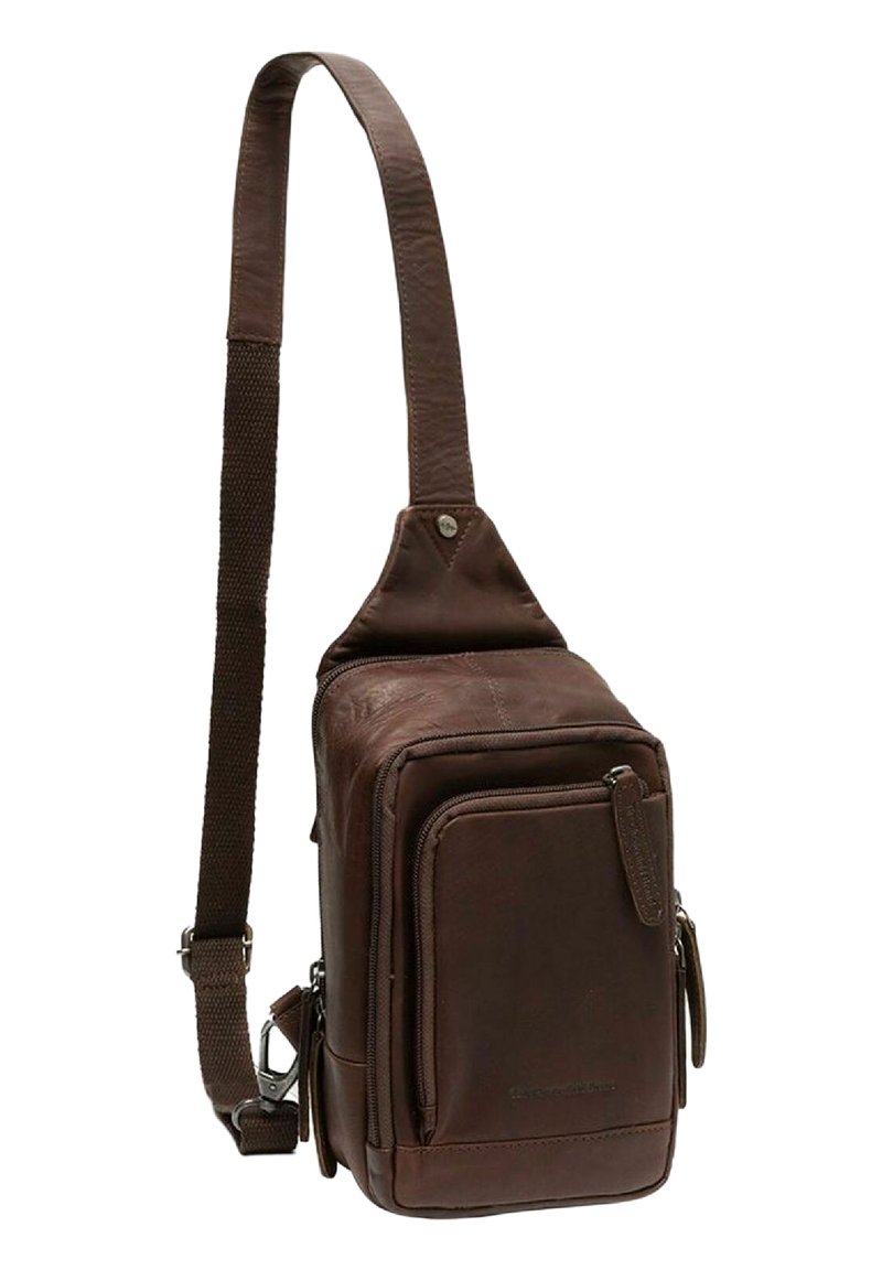Sac en cuir marron avec une sangle réglable unique, plusieurs compartiments zippés et une finition texturée. Forme rectangulaire compacte.