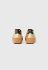 Sneaker metallici dorati con dettagli neri, suole piatte, forma arrotondata, schienali imbottiti e suole esterne in gomma testurizzata.