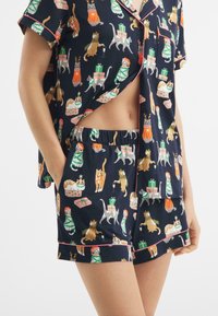 Granatowy zestaw piżamowy z kotami i wzorami prezentów, krótki rękaw z guzikiem i kieszenią, szorty z elastycznym pasem i kontrastowym wykończeniem.