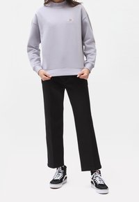 Grå sweatshirt med hög krage och ribbat fåll, som matchas med svarta vida byxor och svarta högskor med vita snörningar.