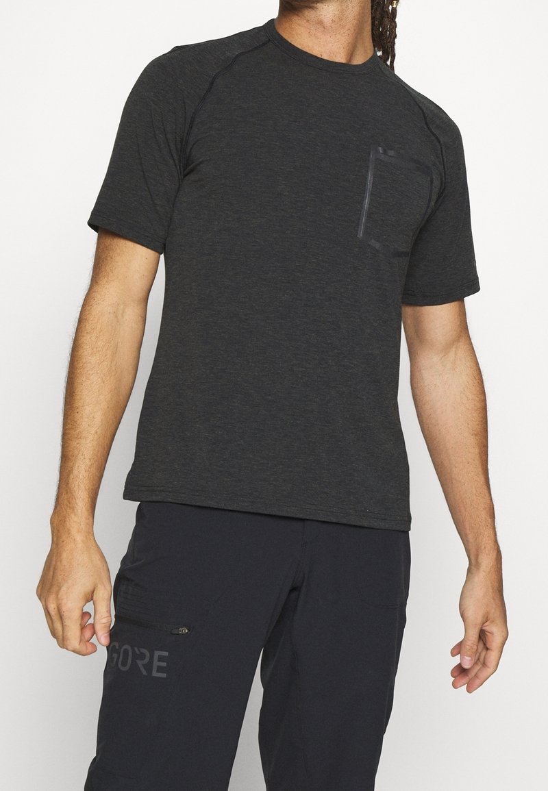 Svart ljung kortärmad t-shirt med raglanärmar och en ficka på vänster bröst. Mjuk tyg med en slät struktur och en figurnära passform.