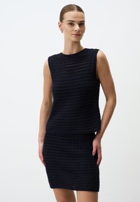 Ensemble en tricot bleu marine composé d'un top sans manches avec un motif texturé et d'une jupe ajustée, mettant en avant un tricot ajouré et des formes définies.